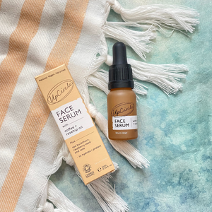Upcircle face serum bottle and packaging on a textured surface with tassels