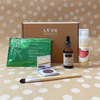 Subscription box  with Zatik Eye serum, TUSOL matcha smoothie mix, Vielle Serum bottle, Orglamix brush, and Flyte.70 Eyeshadow on a polka dot background.